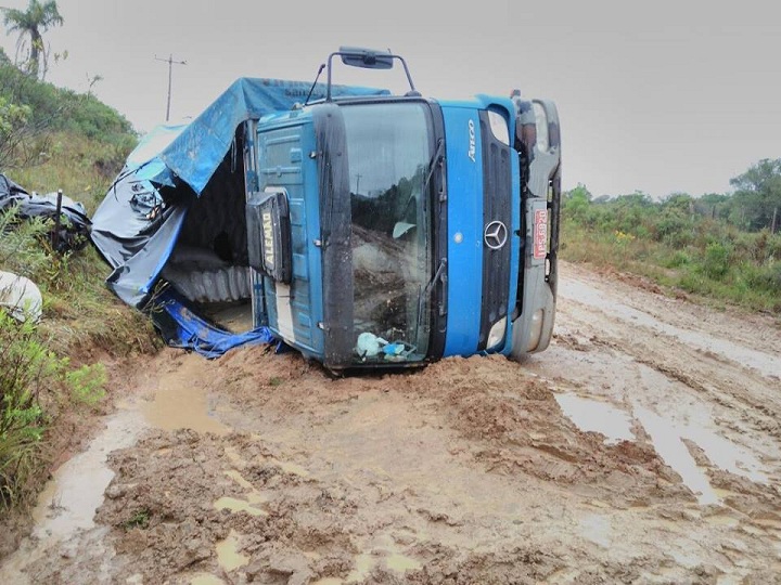 Devido as condições da estrada, caminhão tombou no meio da lama