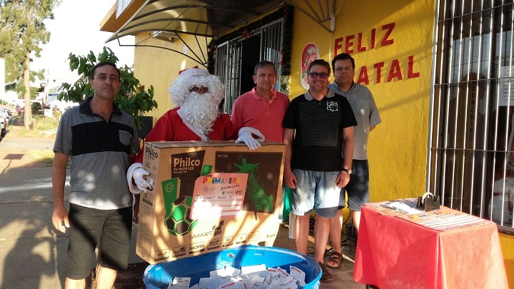 Coordenador da Secretaria de Cultura Fabiano Aquere, proprietário da Empório Econômico Jacir Luvison, assessor da Secretaria de Cultura Márcio Vieira e o vice-presidente da CDL Clarque Rostan, junto ao Papai Noel e um dos prêmios do último sorteio, uma TV 39 polegadas
