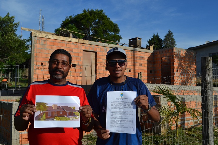 Valtair e o filho Jonata exibem o contrato do terreno e o projeto da nova casa que a família já está construindo